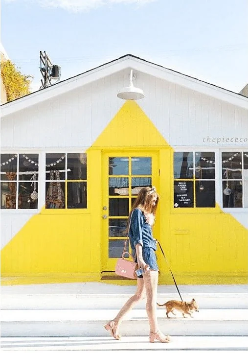 Yellow shopfront with a pedestrian and dog passing