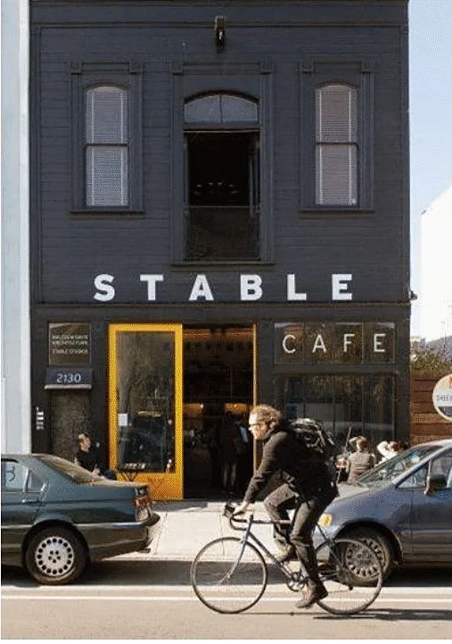 Two-storey brick building housing a cafe, cyclist passing